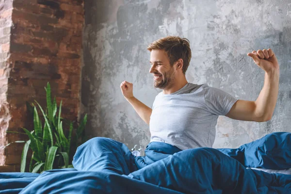 Handsome young man stretching in bed during morning time at home — Stock Photo