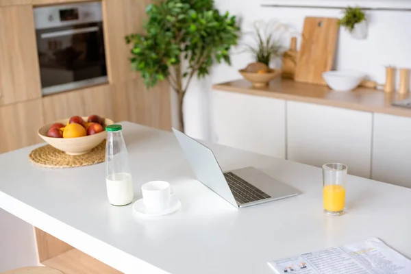 Foyer sélectif de l'ordinateur portable, café et jus de fruits frais sur la table à la cuisine — Photo de stock