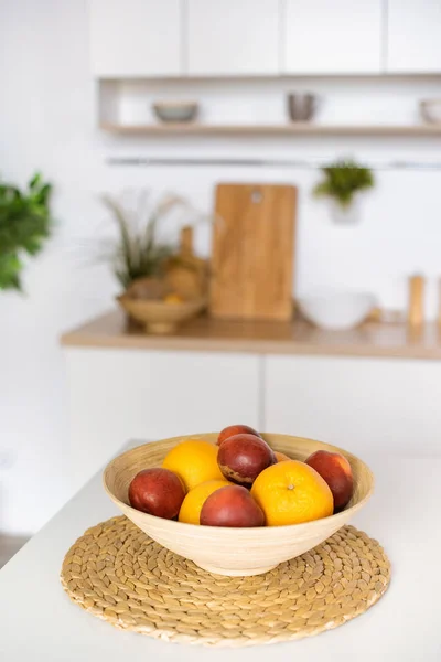 Close up view of oranges and plums in bowl at kitchen table — Stock Photo