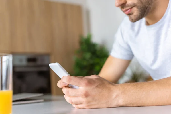 Cropped image of man using smartphone at kitchen table — Stock Photo