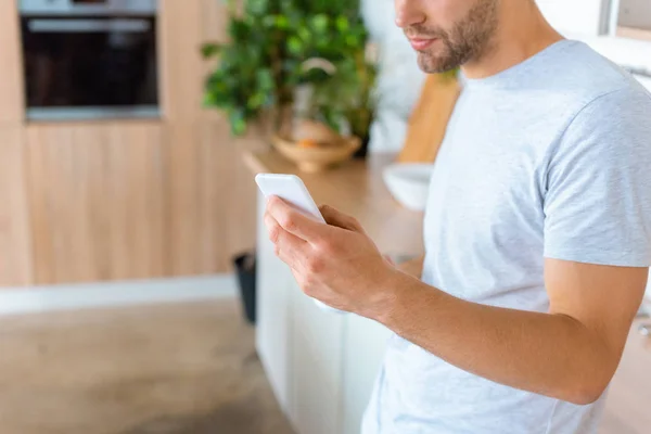 Cropped image of man using smartphone at kitchen — Stock Photo