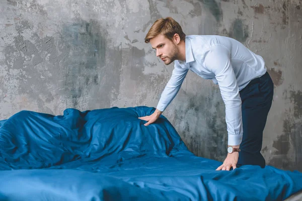Homem de negócios focado cobrindo cama por azul coverlet em casa — Fotografia de Stock