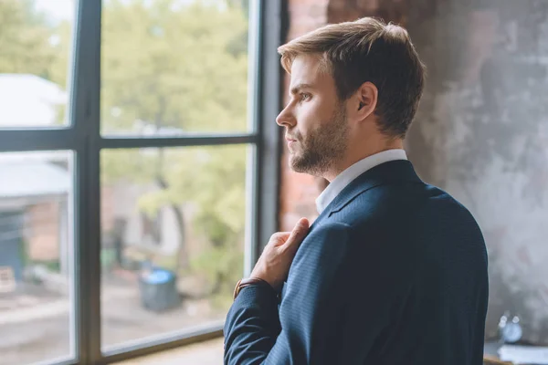 Selective focus of young businessman putting on jacket at home — Stock Photo