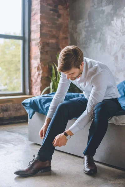Молодой бизнесмен завязывает шнурки в спальне дома — Stock Photo