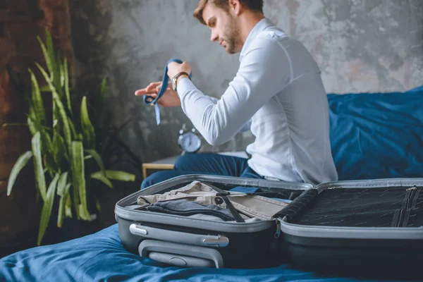 Selective focus of businessman packing luggage in suitcase in bedroom at home — Stock Photo