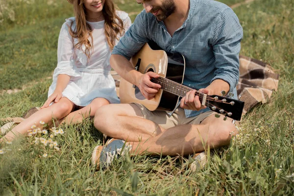 Vue partielle de l'homme jouant de la guitare acoustique à la petite amie souriante en été classé — Photo de stock