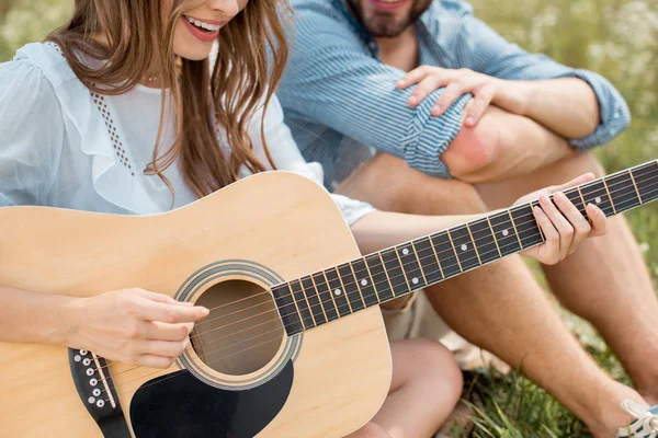 Vista parcial de la mujer sonriente tocando la guitarra acústica a novio en verano archivado - foto de stock