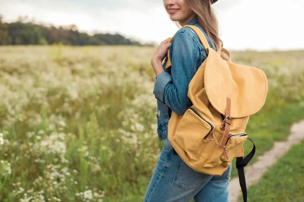 Plan recadré de femme avec sac à dos jaune debout dans le champ — Photo de stock