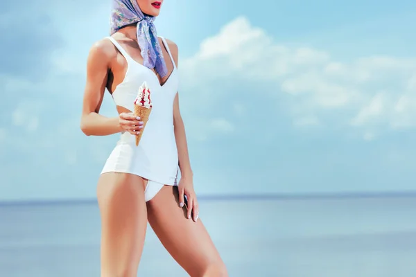 Cropped view of woman in retro swimsuit holding ice cream in waffle cone — Stock Photo