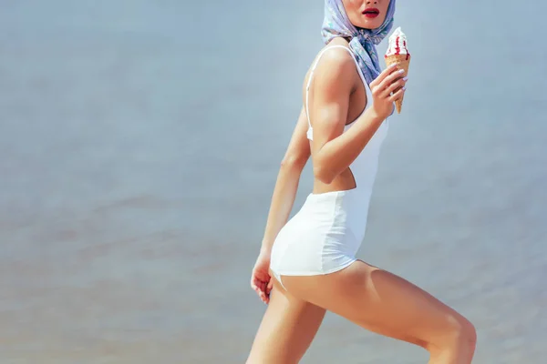 Cropped view of girl in vintage white swimwear holding waffle cone with ice cream — Stock Photo