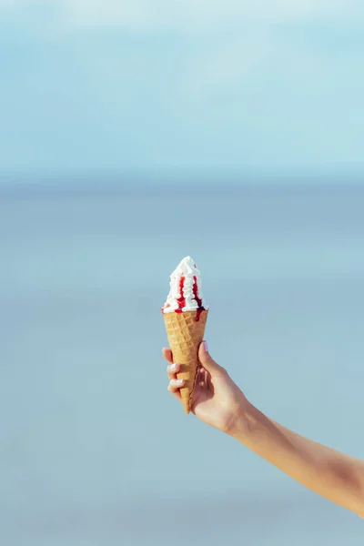 Cropped view of female hand with sweet ice cream in waffle cone — Stock Photo