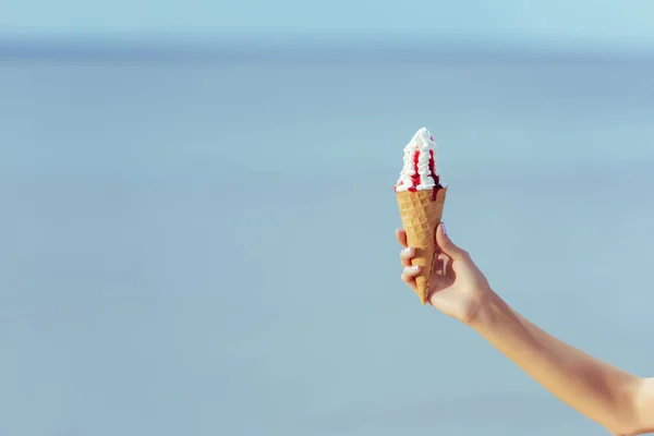Partial view of woman holding waffle cone with sweet ice cream in hand — Stock Photo