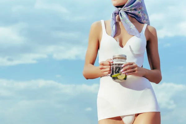 Cropped view of girl in white vintage swimsuit holding mason jar with fresh lemonade — Stock Photo