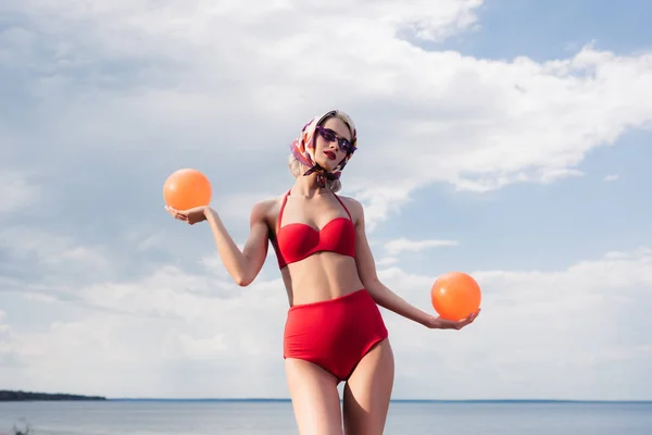 Menina elegante atraente em biquíni vintage e cachecol de seda posando com bolas no mar — Fotografia de Stock