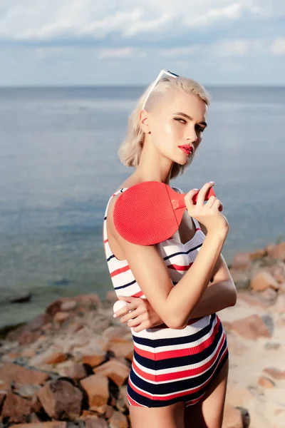 Attractive stylish sportswoman in swimsuit posing with ping pong racket and ball — Stock Photo