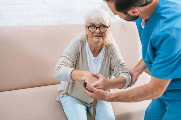 Plan recadré de l'infirmière masculine aidant la femme âgée avec bâton de marche — Photo de stock