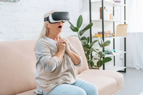 Shocked senior woman using virtual reality headset at home — Stock Photo