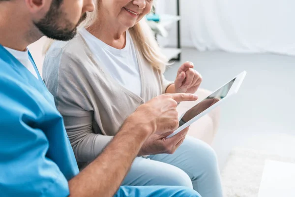 Cropped shot of male nurse and senior woman using digital tablet together — Stock Photo