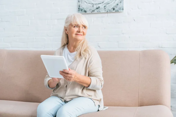 Glückliche Seniorin nutzt digitales Tablet und schaut weg — Stockfoto