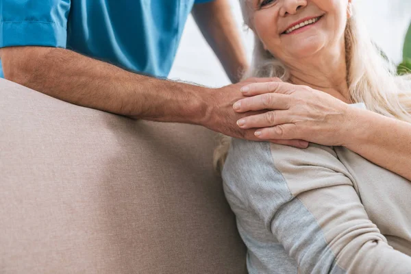 Plan recadré d'une femme âgée souriante tenant la main d'un soignant — Photo de stock