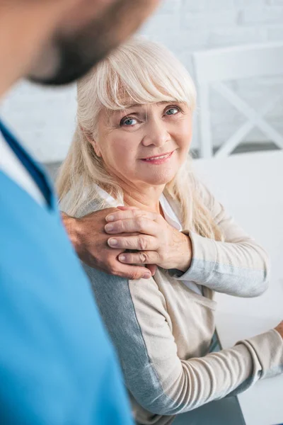 Plan recadré de travailleuse sociale et de femme âgée souriante tenant la main — Photo de stock