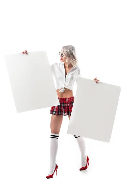 Jovem mulher sedutora em uniforme universitário segurando banners em branco isolado no branco — Fotografia de Stock