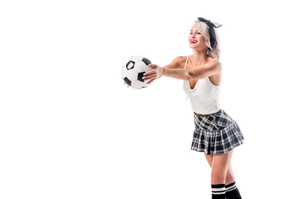 Donna sorridente in seducente plaid gonna studentessa tenendo palla da calcio isolato su bianco — Foto stock