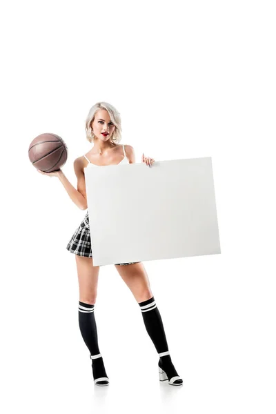 Mulher loira sexy em saia xadrez curto com bola de basquete e banner vazio posando isolado no branco — Fotografia de Stock
