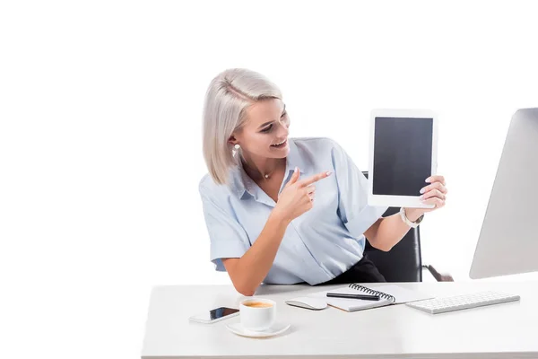 Retrato de mujer de negocios sonriente apuntando a la tableta con pantalla en blanco en el lugar de trabajo aislado en blanco - foto de stock