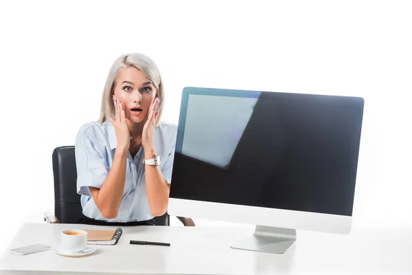 Retrato de empresaria sorprendida sentada en el lugar de trabajo con pantalla de computadora en blanco aislada en blanco - foto de stock