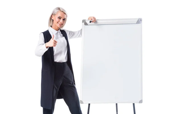 Mulher de negócios sorridente em desgaste formal perto de quadro branco vazio mostrando polegar para cima isolado no branco — Fotografia de Stock