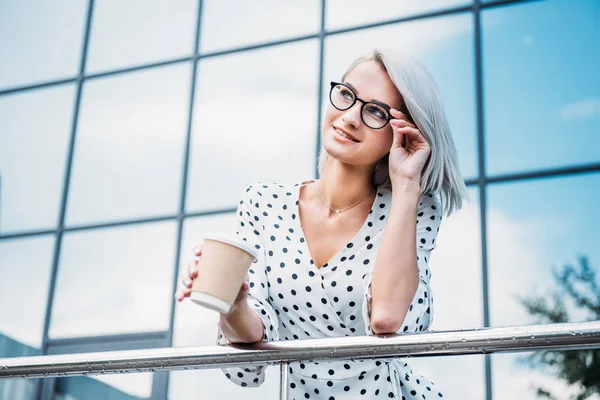 Portrait of stylish businesswoman in eyeglasses with coffee to go in hand on street — Stock Photo