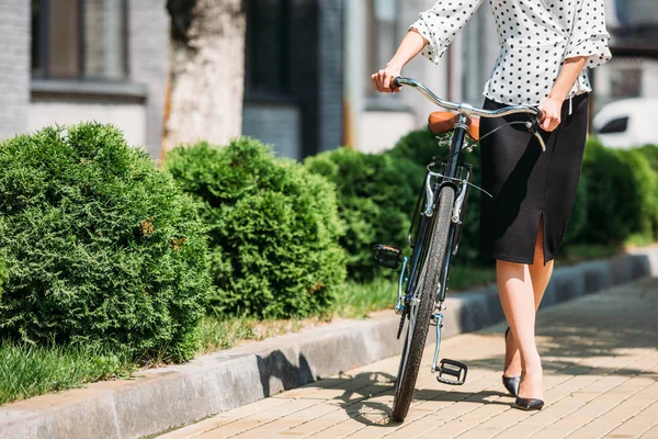 Partial view of businesswoman with retro bicycle walking on street — Stock Photo