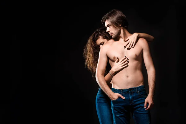 Vista parziale della donna che abbraccia il fidanzato senza maglietta in jeans isolato su nero — Foto stock