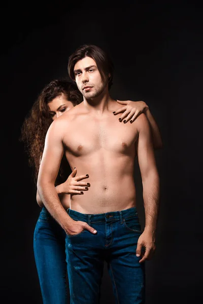 Partial view of woman hugging shirtless boyfriend in jeans isolated on black — Stock Photo