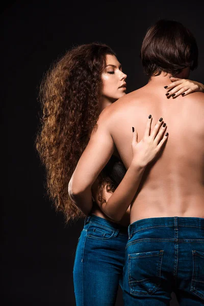 Back view of girlfriend hugging shirtless man isolated on black — Stock Photo