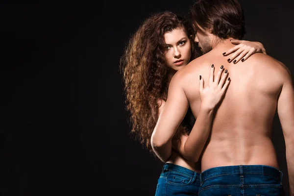 Visão traseira da namorada abraçando o homem sem camisa isolado no preto — Fotografia de Stock