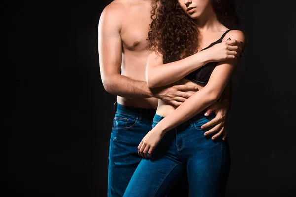 Cropped shot of shirtless couple in jeans hugging isolated on black — Stock Photo