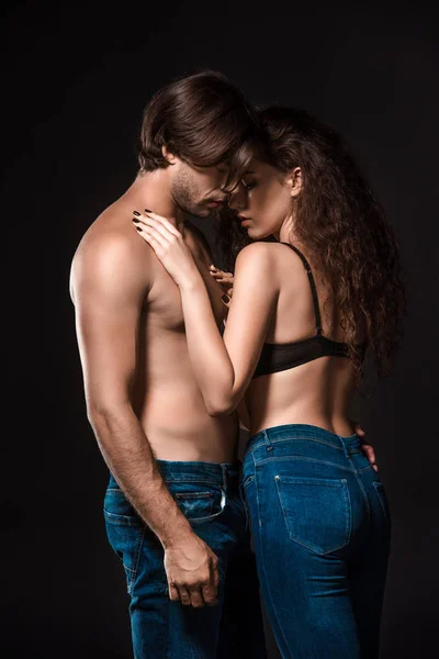 Вид збоку сексуальної без сорочки пара обіймається ізольовано на чорному — стокове фото