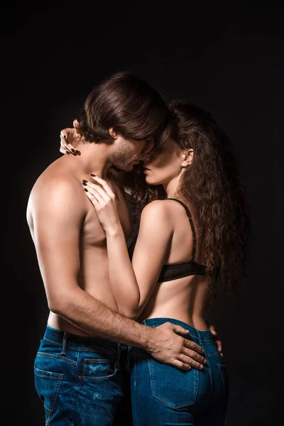 Vista lateral de sexy pareja sin camisa abrazo aislado en negro - foto de stock