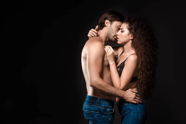 Side view of sexy shirtless couple hugging and kissing isolated on black — Stock Photo