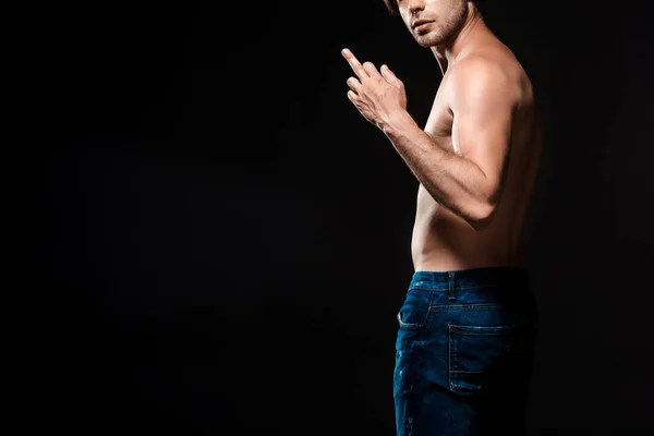 Partial view of shirtless man showing middle finger to camera isolated on black — Stock Photo