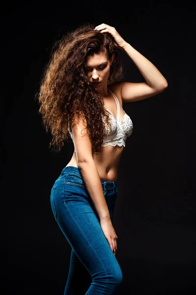 Portrait of beautiful woman in white bra and jeans posing isolated  on black — Stock Photo