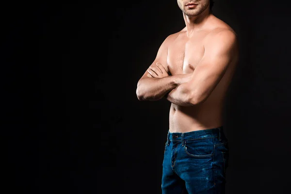 Vista parziale di uomo senza camicia in jeans con le braccia incrociate posa isolata su nero — Foto stock