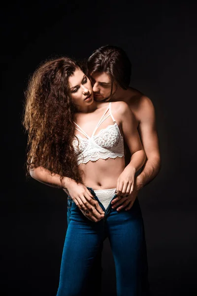 Retrato de homem decolando namoradas jeans isolado no preto — Fotografia de Stock