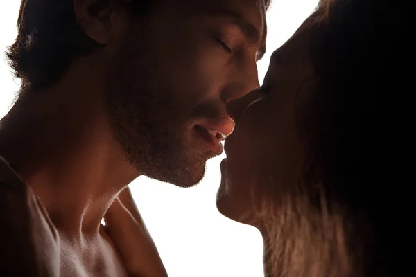 Vista lateral de la pareja besándose de pie cara a cara, aislado en blanco - foto de stock