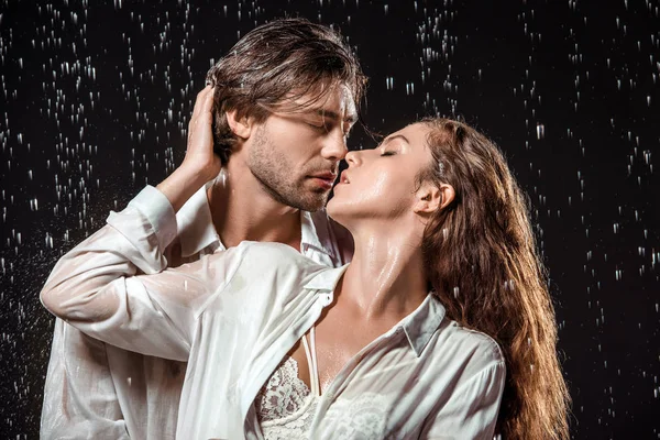 Portrait of seductive couple hugging under rain isolated on black — Stock Photo