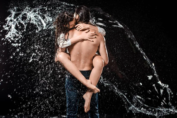 Back view of sexy young couple swilled with water isolated on black — Stock Photo