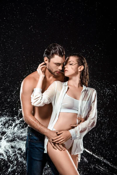 Portrait of seductive couple swilled with water isolated on black — Stock Photo