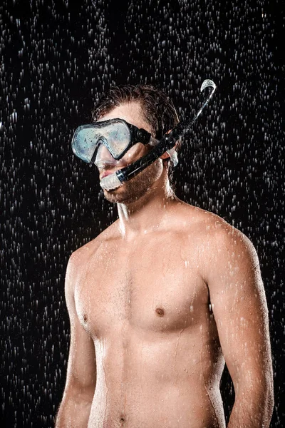 Retrato de hombre sin camisa en máscara de natación con snorkel de pie bajo las gotas de agua aislado en negro - foto de stock
